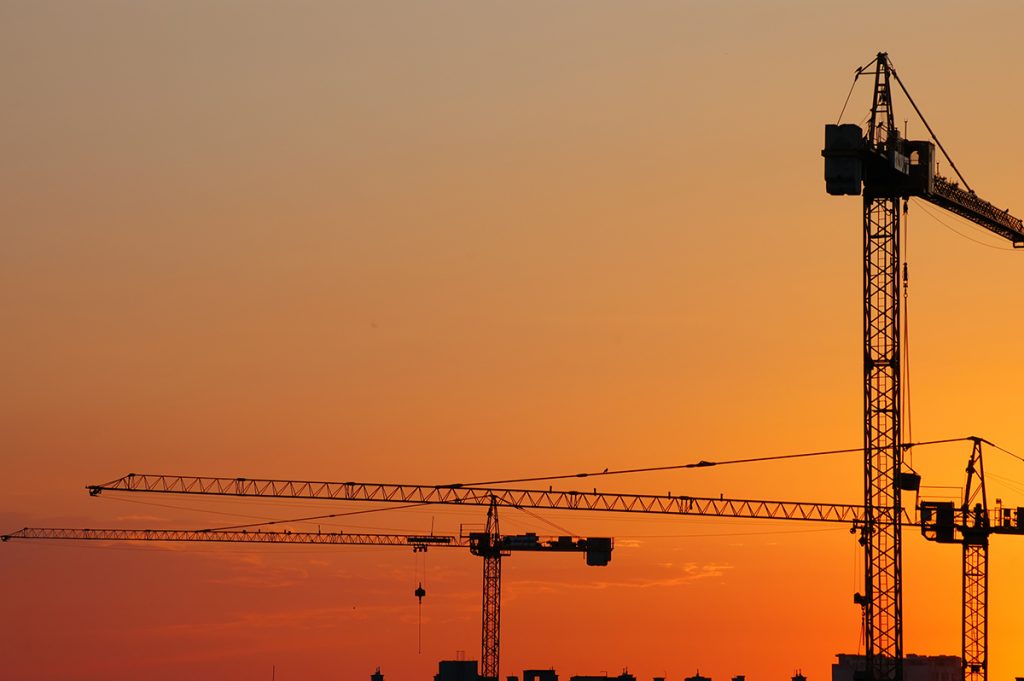 Construction cranes in the sunset