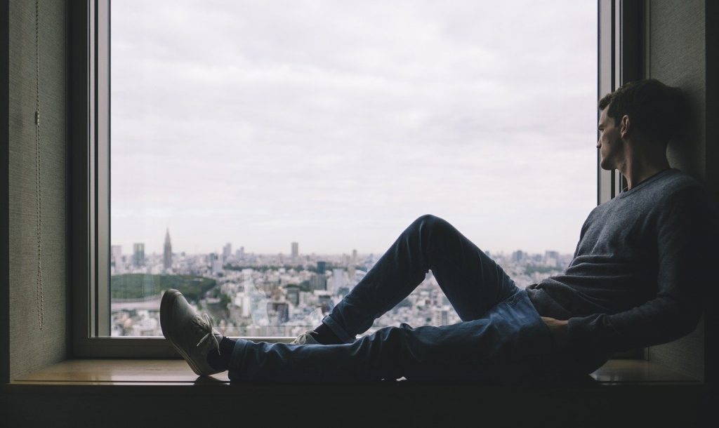 Young business professional sits in window looking out over city