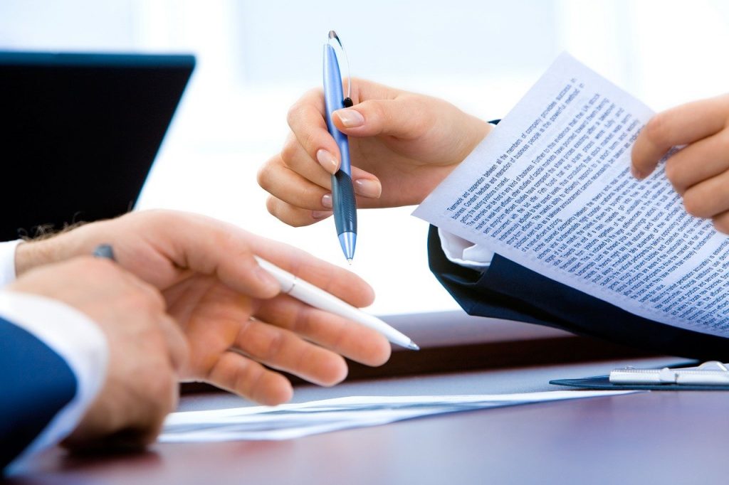 The hands of two people gesticulating over business paperwork