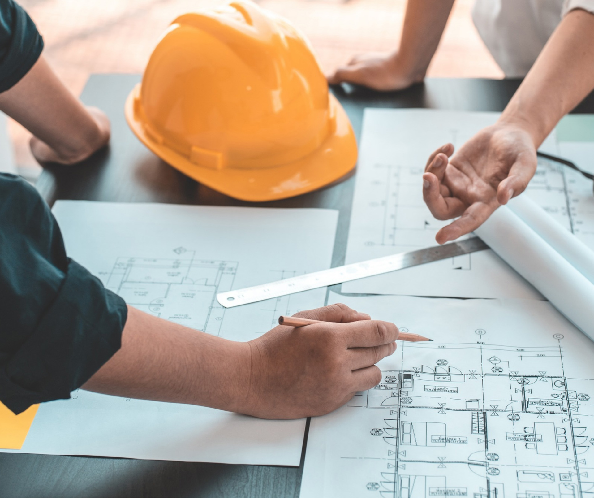 Two people reviewing construction blueprints and plans at a table with a hard hat